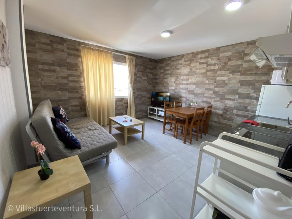 ein Wohnzimmer mit einem Sofa, einem Tisch und einem Klavier in der Unterkunft Edificio Prieto VIV 5 in Puerto del Rosario