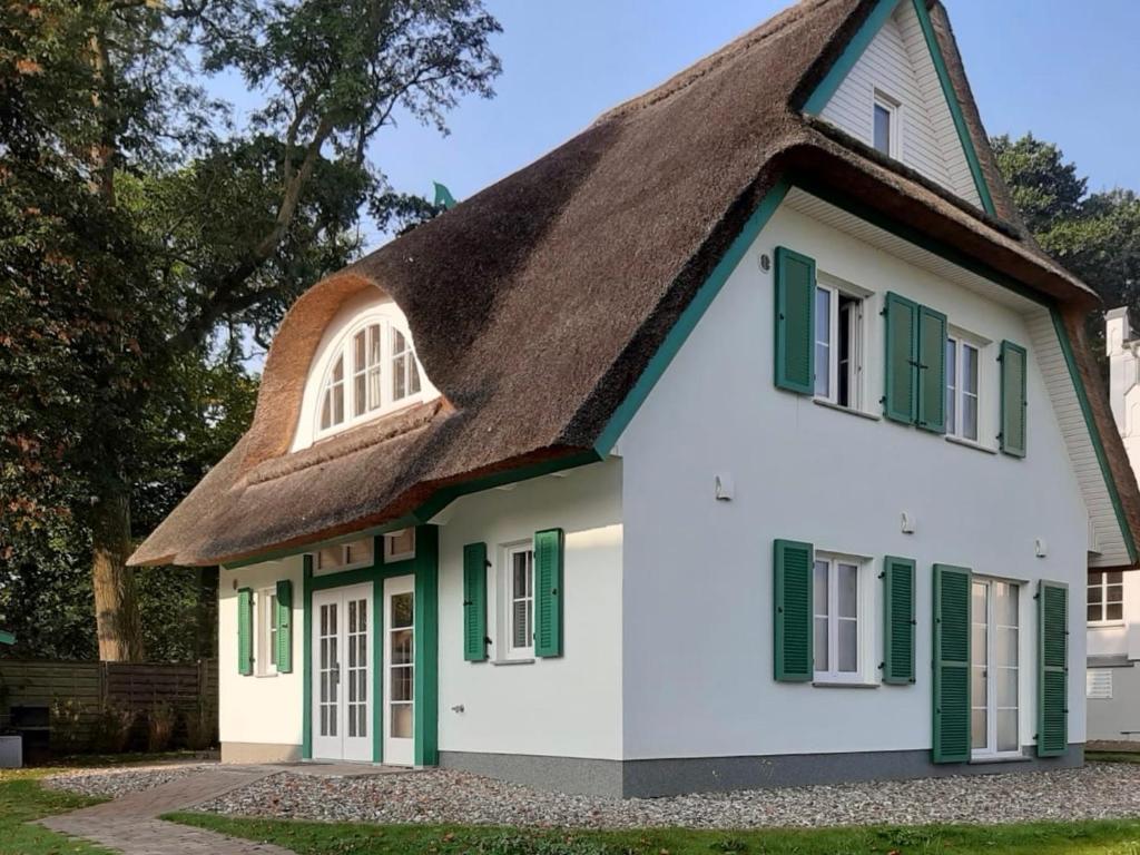 a thatched roof house with green shuttered windows at Traditionelles Reethaus direkt an der Ostsee in Rerik
