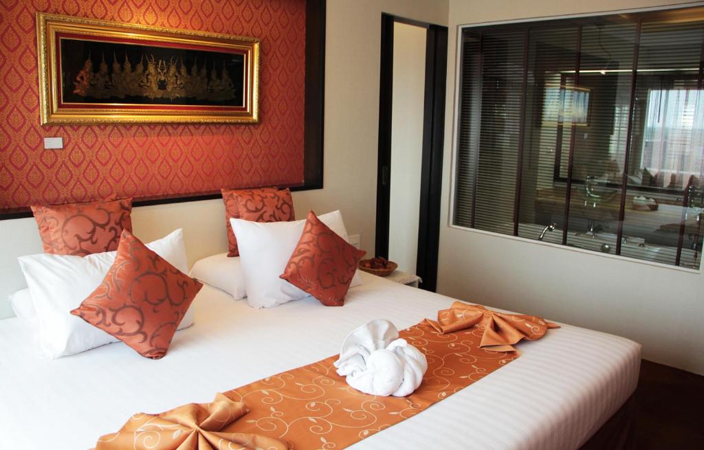 1 dormitorio con 2 camas, paredes de color rojo y ventana en V Verve Service Apartment Hotel en Chachoengsao