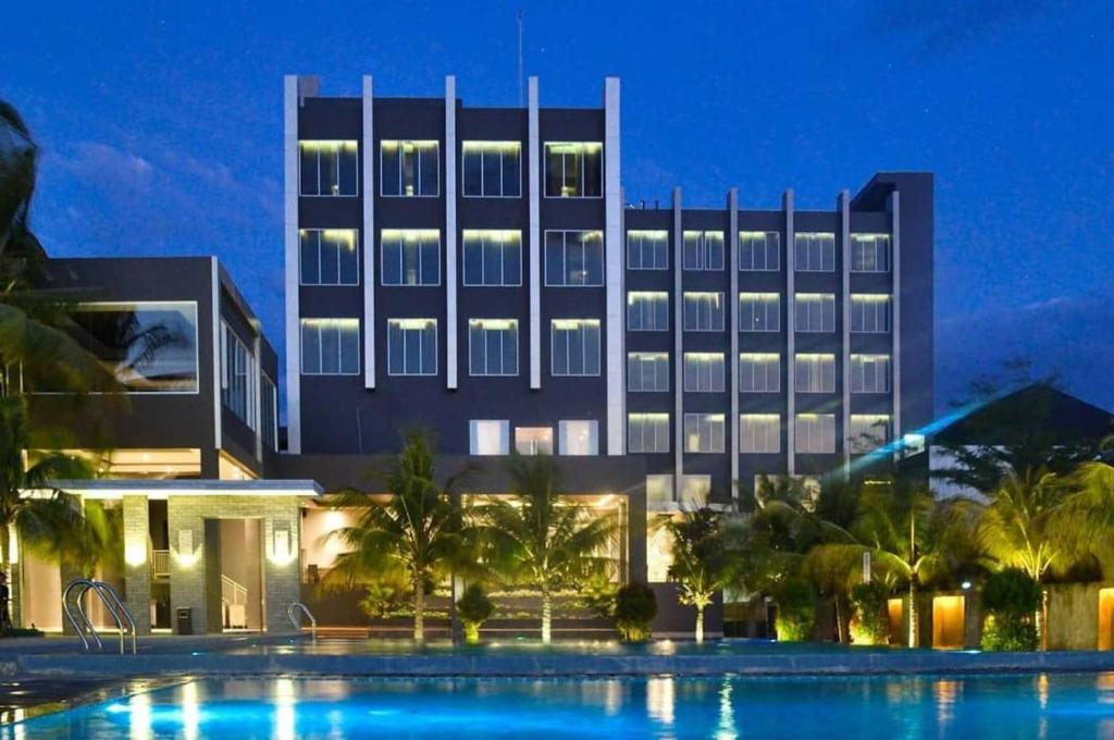 a hotel with a swimming pool in front of a building at Aston Gorontalo Hotel & Villas in Gorontalo
