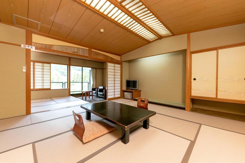 Itoen Hotel New Sakura في نيكو: غرفة معيشة فيها طاولة وكراسي