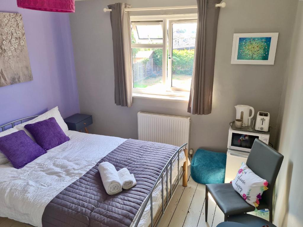 a bedroom with a bed and a chair and a window at love-lyph stays in Watford