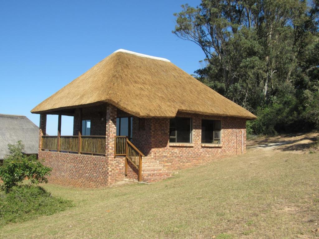 a brick building with a grass roof on a field at Pomeroy Lodges in Rietrivier