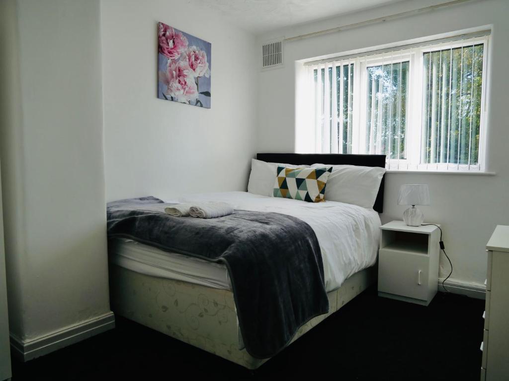 a white bedroom with a bed with a window at Reddish comfort house in Manchester