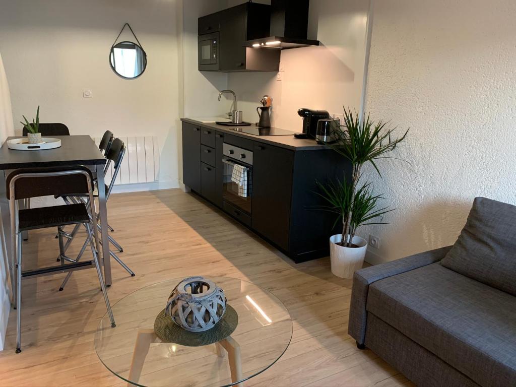 a living room with a couch and a table and a kitchen at Logement rénové et moderne au Sacré Coeur Cholet in Cholet