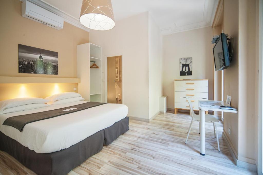 a bedroom with a bed and a desk and a television at Residence Metropole Toulouse in Toulouse