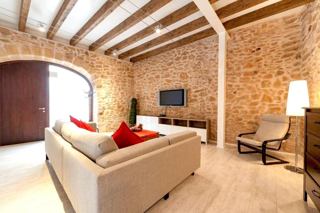 a living room with a white couch and a tv at Casa Sa Pedra, en el centro histórico de Alcudia in Alcudia