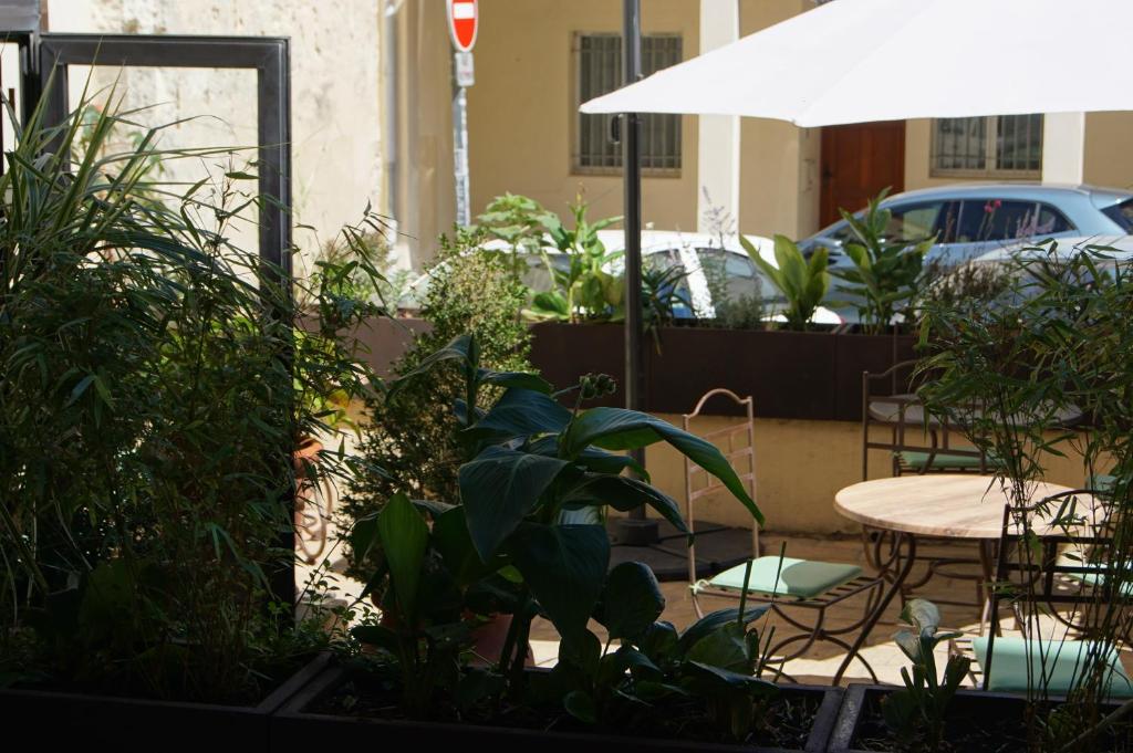 a patio with a table and chairs and plants at Hôtel La Muette in Arles