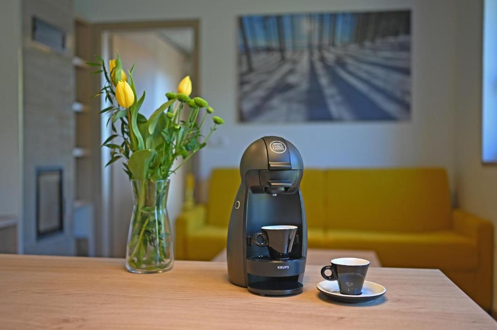a coffee maker and a vase with flowers on a table at Vetrnik Depandance Hotelu Jirinka in Dolní Morava