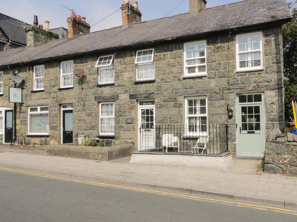 an old stone building with white windows on a street at Llawenfan in Criccieth