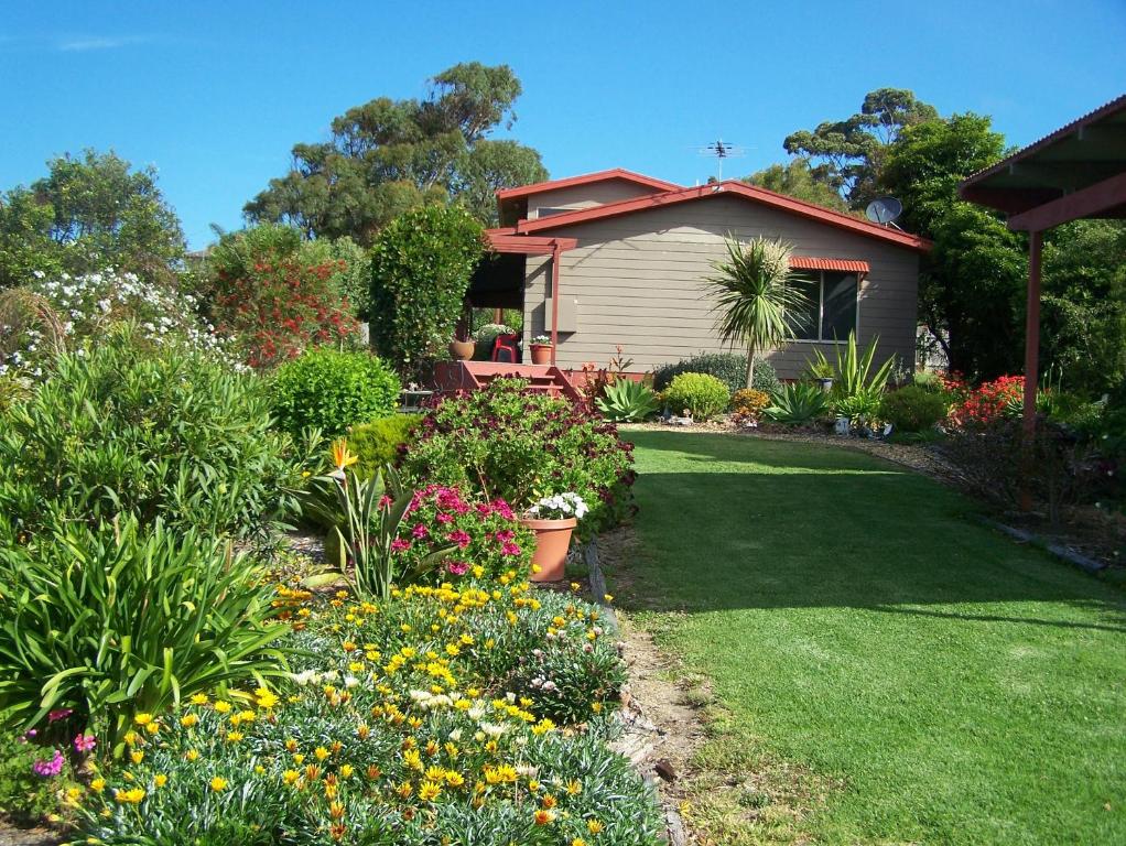 a garden with colorful flowers and a house at Monaro Cottage in Eden