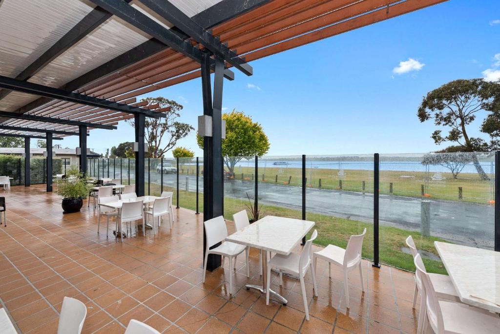 a patio with tables and chairs and a view of the ocean at Bayside Hotel in St Helens
