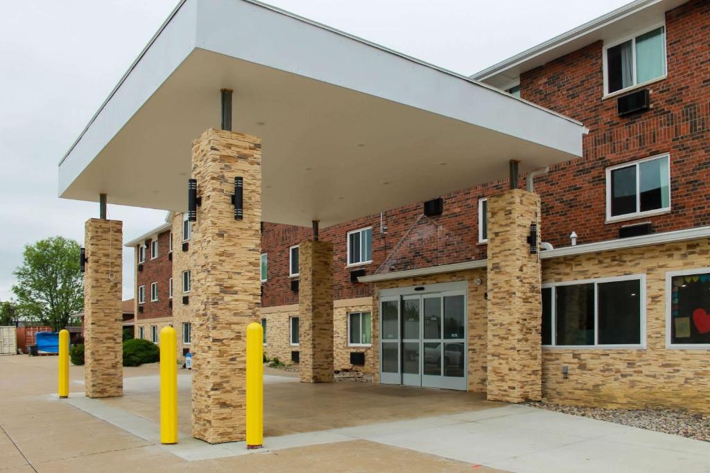 a brick building with yellow poles in front of it at Clarion Pointe Bettendorf - Quad Cities in Bettendorf