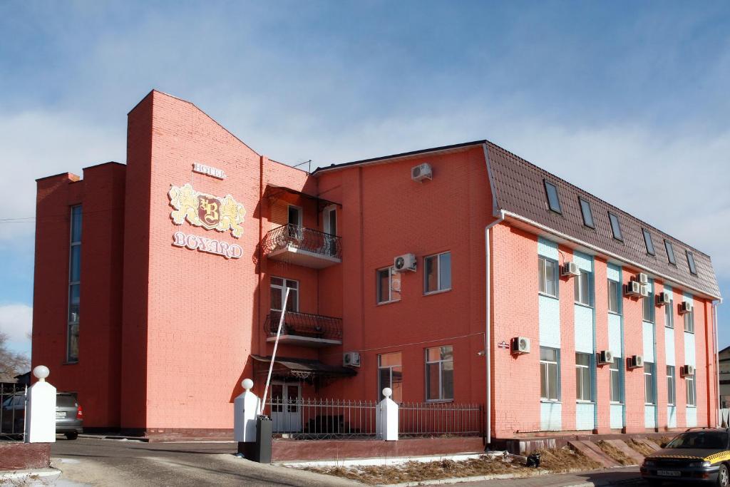 un edificio rojo con un cartel en el costado en Hotel Boyard, en Ussuriisk