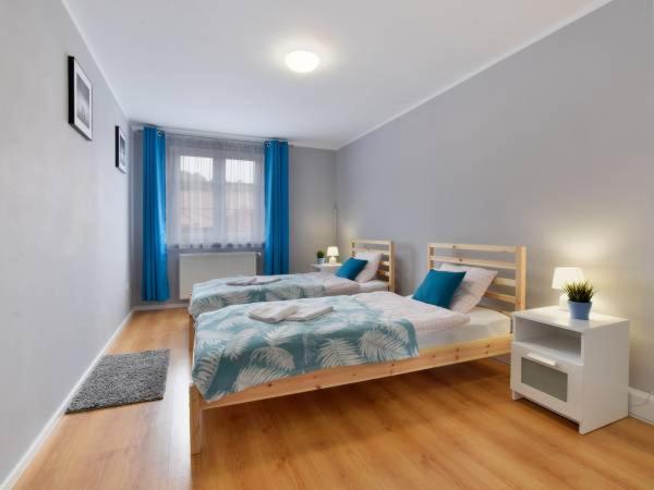 1 dormitorio con 2 camas y cortinas azules en Apartament w Mieście en Duszniki Zdrój