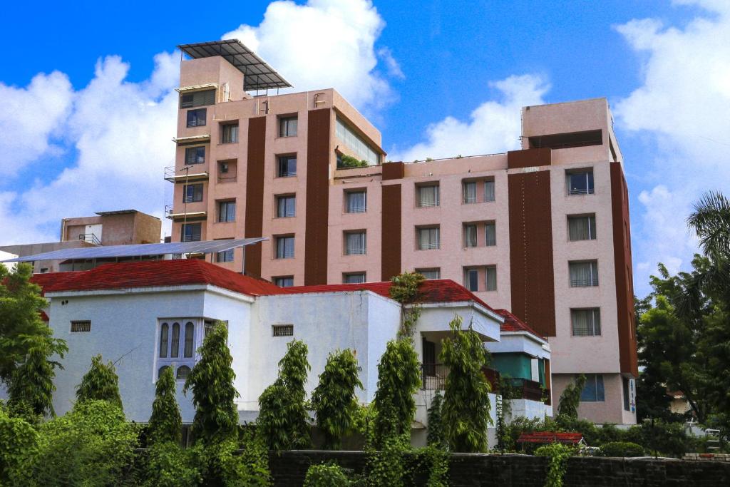 un edificio alto con una casa blanca delante de ella en The Park Residency, en Ahmedabad