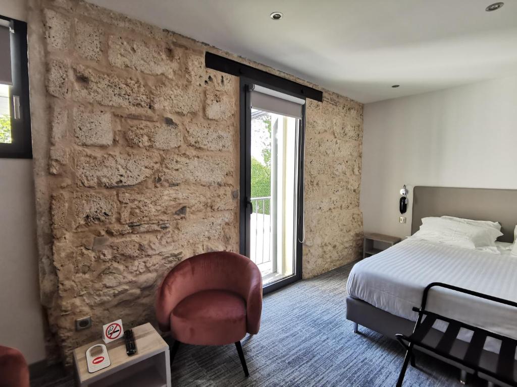 sypialnia z łóżkiem i ceglaną ścianą w obiekcie Hotel de la Couronne w Aix-les-Bains