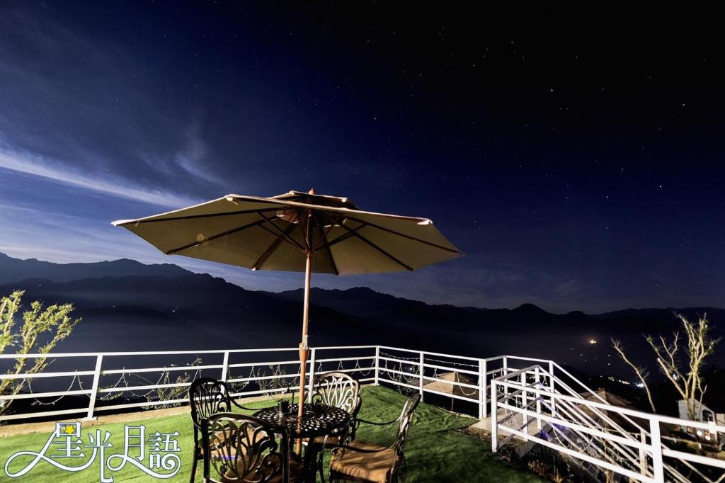 a table and chairs under an umbrella at night at Starhome Cottage in Ren'ai