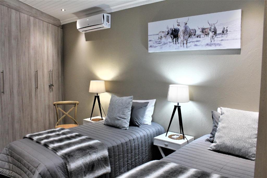 a bedroom with two beds and a tv on the wall at @Home in the East in Pretoria