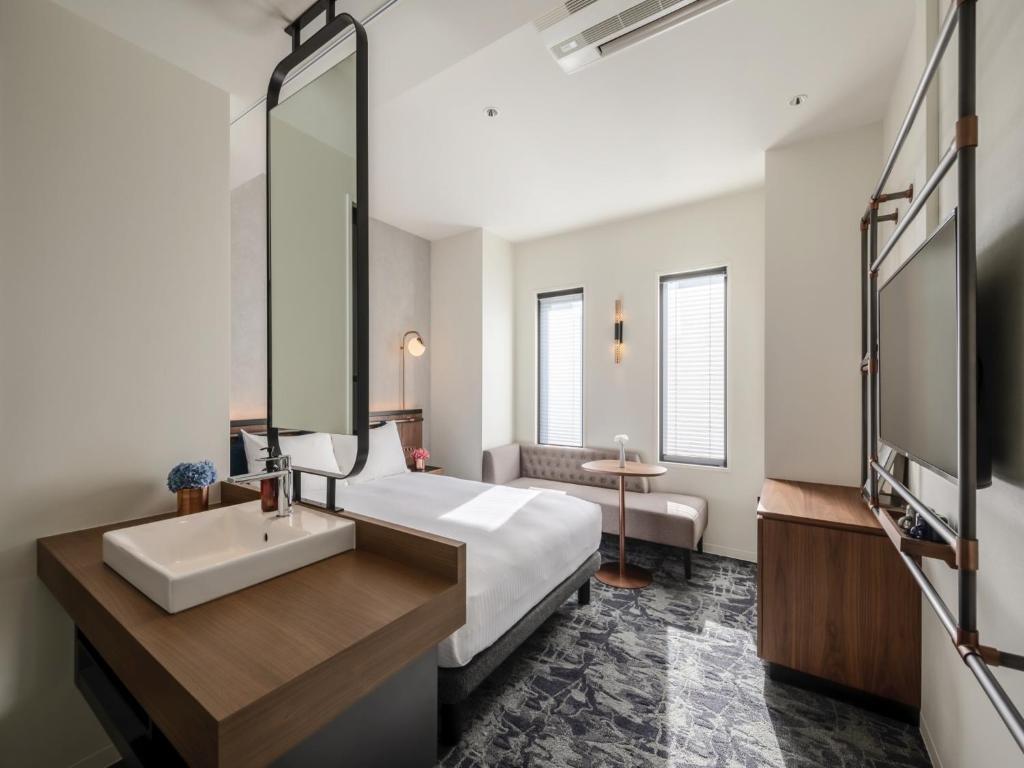 Schlafzimmer mit einem Bett, einem Waschbecken und einem Spiegel in der Unterkunft THE LIVELY HONMACHI OSAKA / Vacation STAY 76674 in Osaka