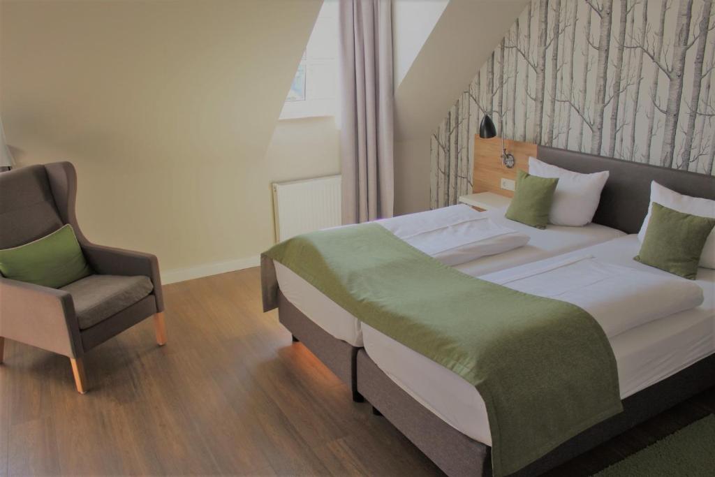 ein Schlafzimmer mit einem Bett und einem Stuhl in der Unterkunft Hotel Eifelbräu in Bitburg