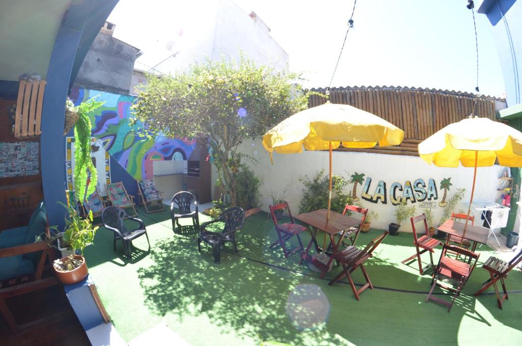 une terrasse avec des chaises, des tables et un parasol dans l'établissement La Casa Hostel, à Arraial do Cabo