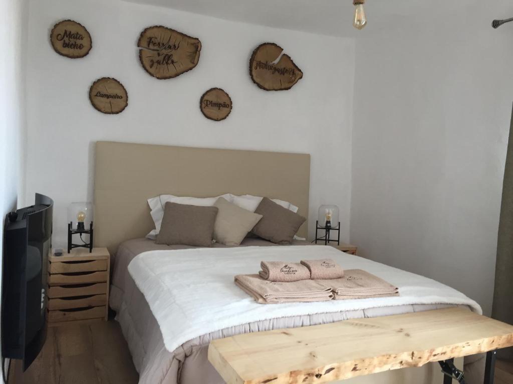 um quarto com uma cama e uma televisão e relógios na parede em Lambisco- Alojamento local em Alfândega da Fé