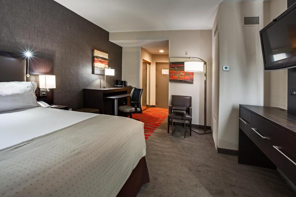 a hotel room with a bed and a desk at Holiday Inn Express & Suites Naples Downtown - 5th Avenue by IHG in Naples