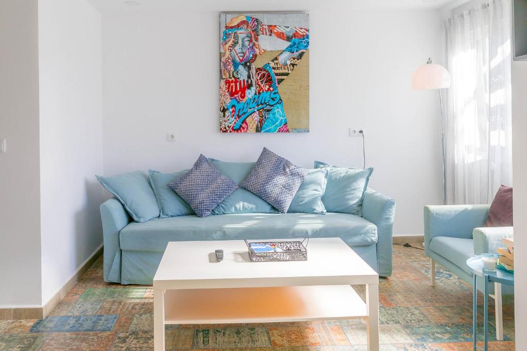 ein Wohnzimmer mit einem blauen Sofa und einem Tisch in der Unterkunft SUNCASTLE APARTAMENTOS ALICANTE -With Sunny Rooftop Terrace And Barbecue in Alicante