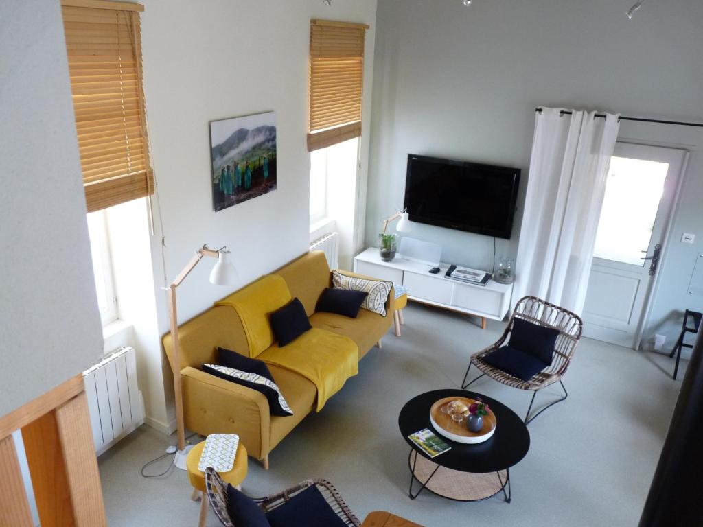 a living room with a yellow couch and a tv at La Maison de Madame Baudy in Giverny