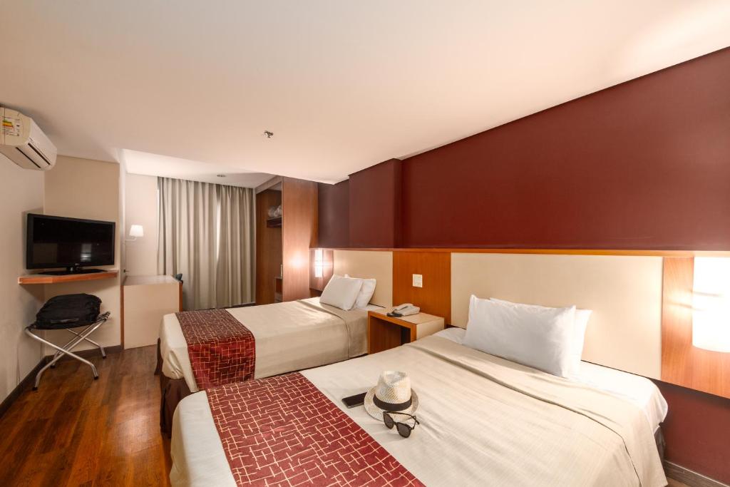 a hotel room with two beds and a television at Rede Andrade CWB in Curitiba
