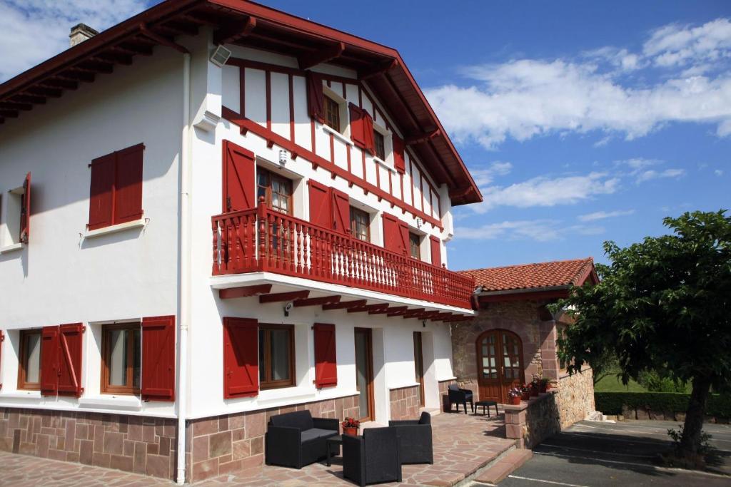 a white building with red shutters on it at Apartamentos Armua in Zugarramurdi