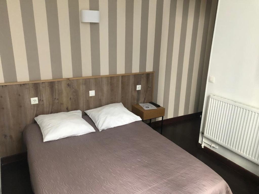 um quarto com uma cama com duas almofadas em Hôtel Résidence Champerret em Levallois-Perret