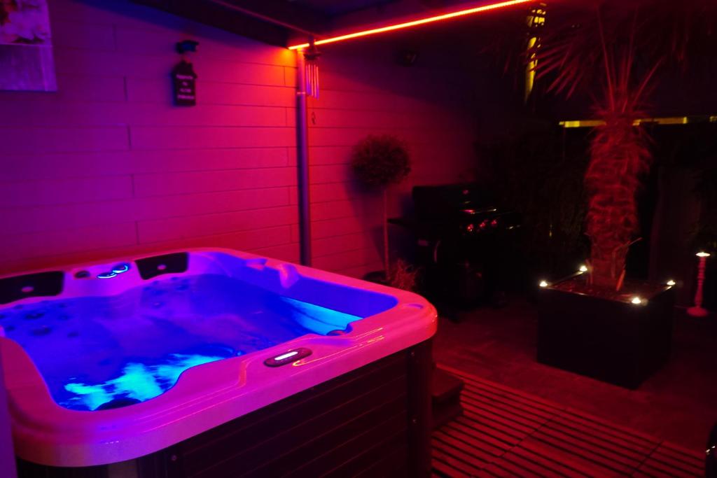 einen Whirlpool in einem Zimmer mit lila Lichtern in der Unterkunft Gites N Spa in Tourcoing