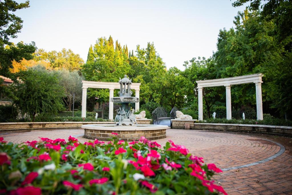 fontanna w ogrodzie z różowymi kwiatami w obiekcie La Tenuta di Rocca Bruna Country Resort w mieście Tivoli
