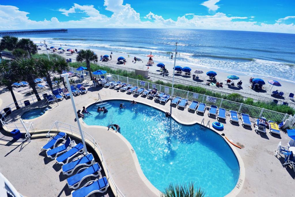 a swimming pool with chairs and the beach at Deluxe Ocean Front Two-Bedroom Condo in Sandy Beach Resort in Myrtle Beach