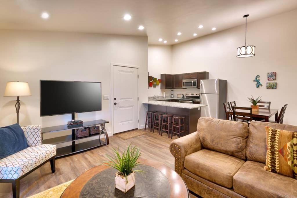 a living room with a couch and a tv and a kitchen at 5I Cozy Family Friendly Moab Condo in Moab