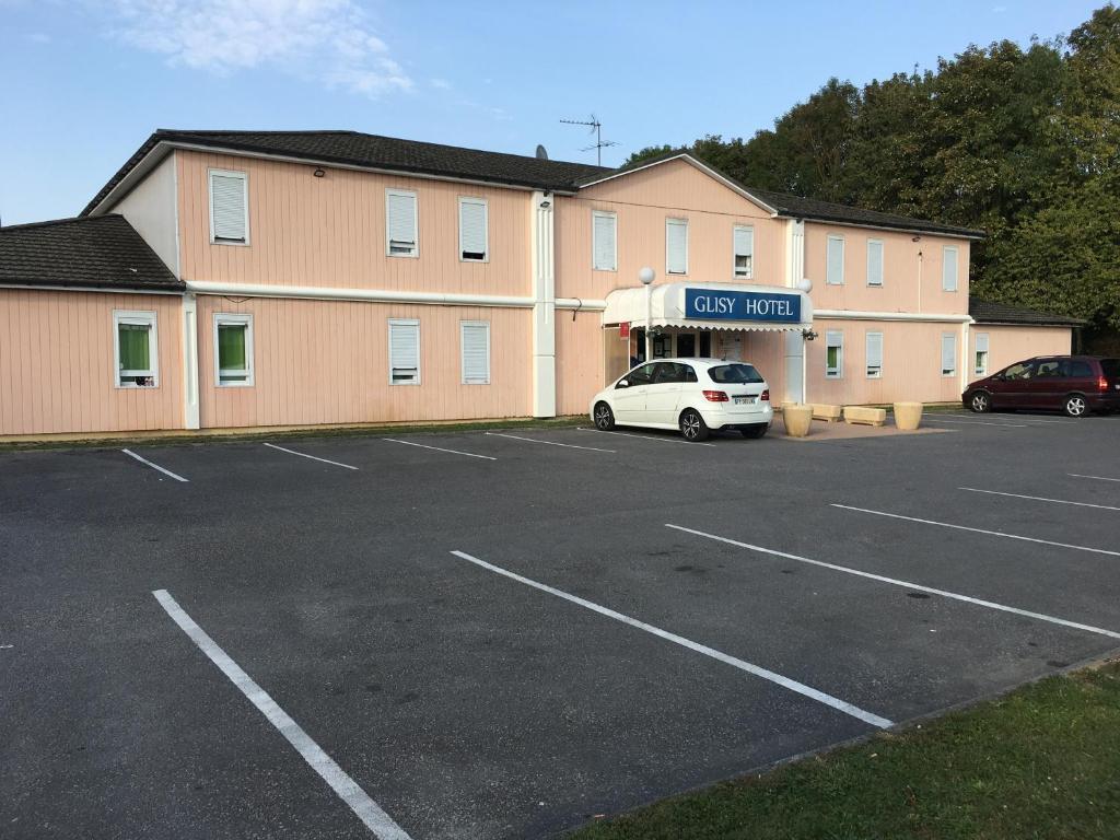 une voiture garée dans un parking en face d'un bâtiment dans l'établissement Glisy Hôtel, à Glisy