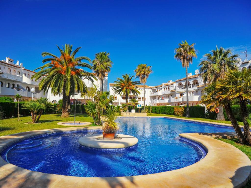 a large swimming pool with palm trees and buildings at Apartment San Esteban by Interhome in Jávea