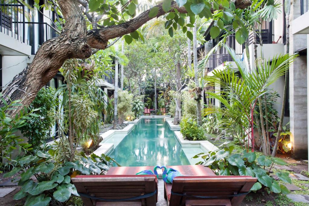 a swimming pool in the middle of a courtyard with trees at S'cape Condotel in Sanur