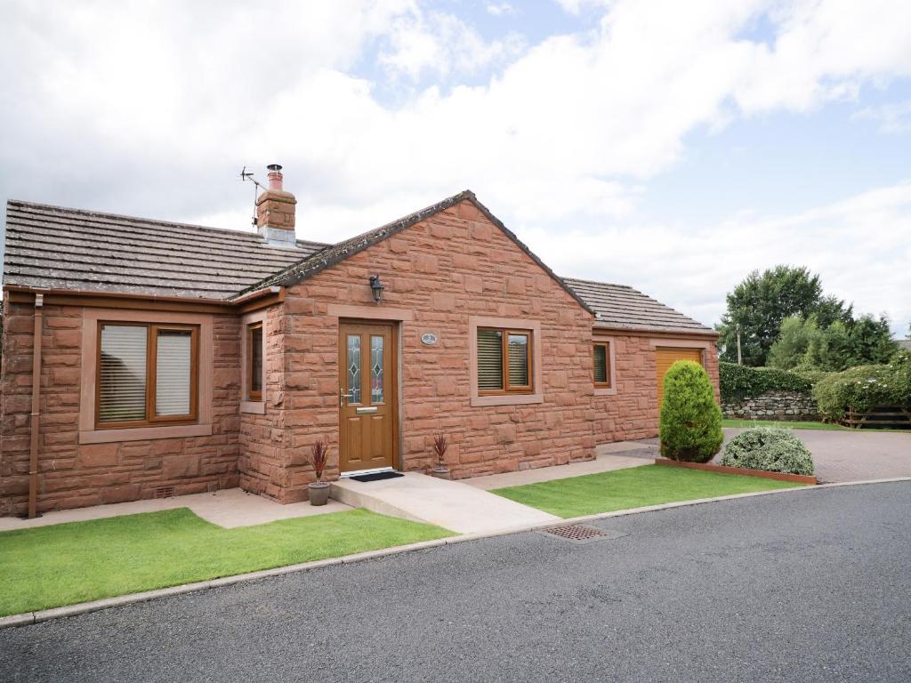 a home with a brick house with a driveway at Cornerways in Kirkby Thore