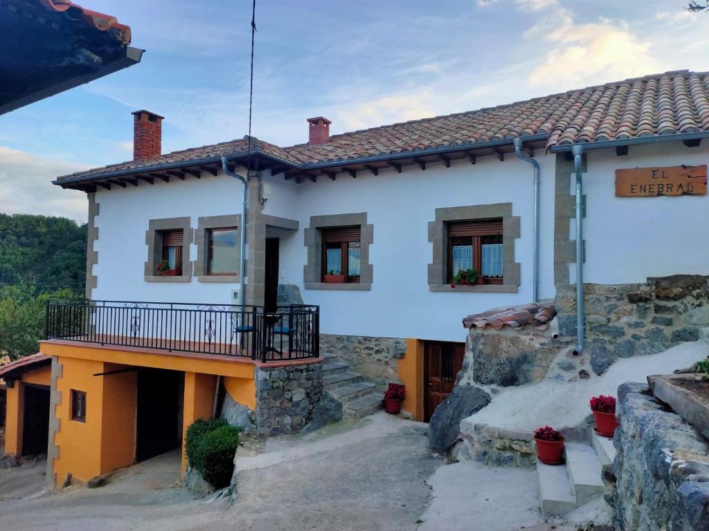 a white house with a balcony on top of it at Casa Rural el Enebral en Potes Picos de Euopa in Colio
