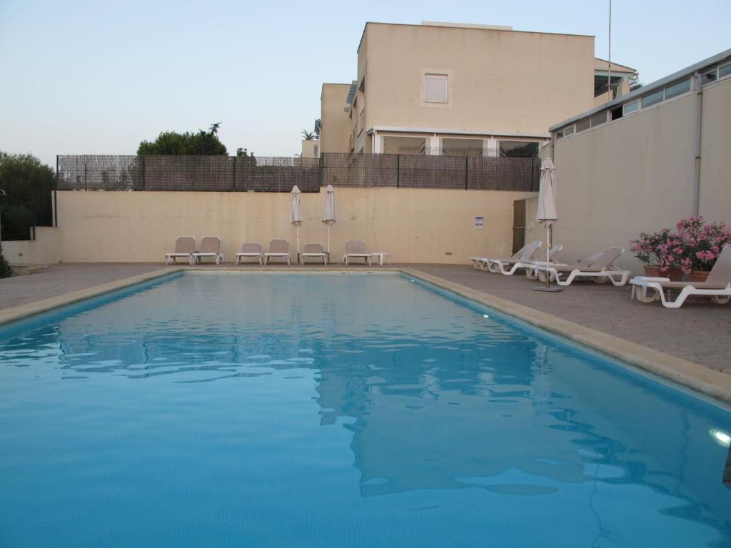 a swimming pool with chairs and a building at Apartment Penthouse Wohnung in Cala Romàntica