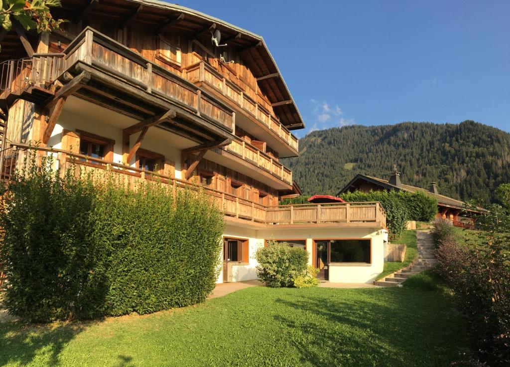 un bâtiment avec une cour verdoyante devant lui dans l'établissement Cordée Côté Sud, à Morzine