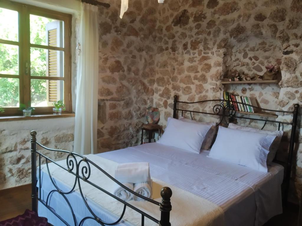 een slaapkamer met een bed in een stenen muur bij The old stone house in Paramythia