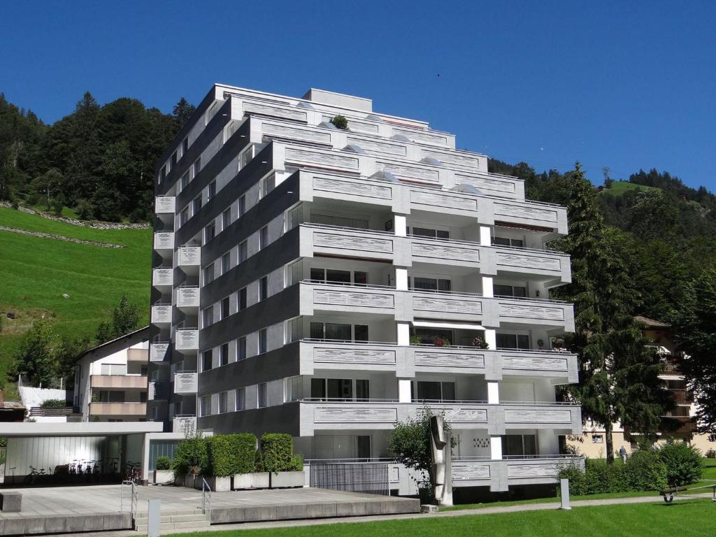 ein hohes weißes Apartmenthaus mit einem Hügel im Hintergrund in der Unterkunft Apartment Sunnmatt 752 by Interhome in Engelberg