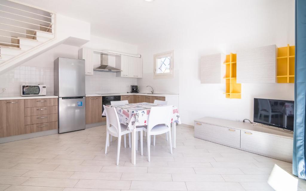 una cucina bianca con tavolo e sedie di Villetta Massimo climatizzata con giardino privato a Viddalba