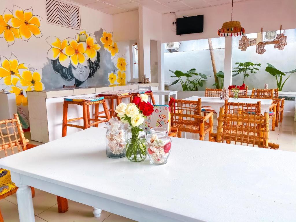 a white table with vases of flowers on it at Papaya Guest House Nungwi in Nungwi