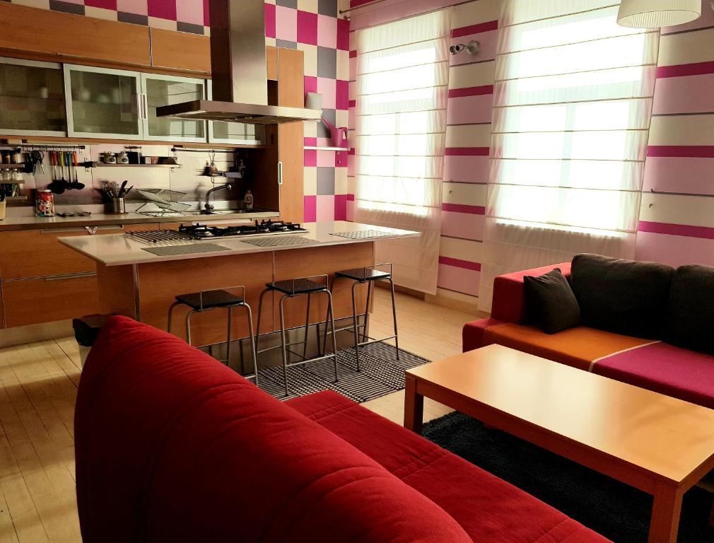 a living room with a red couch and a kitchen at Fuksija House in Daugavpils