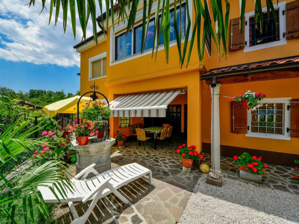 a yellow house with two white benches in front of it at Apartment Villa Karolina by Interhome in Opric